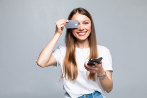 cheerful excited young woman with mobile phone credit card